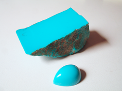 Photo of a piece of rough Turquoise with no matrix and nice blue Turquoise cabochon cut from that material.