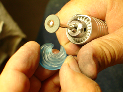 Shows me using a diamond tool in a carving hand tool to shape and carve the blue topaz.