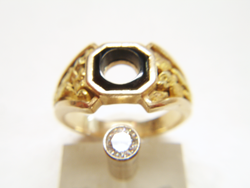 Photo of a nugget style ring with a black Onyx in the middle and a Diamond in a gold tube next to the ring.