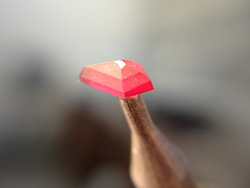 A Ruby being faceted into a kite shape.