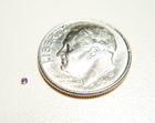 A thumbnail photo of a very tiny round Amethyst next to a dime.