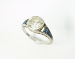 A white gold antique Diamond ring with blue Sapphires, and one is missing.