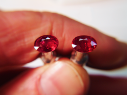 Shows me holding 2 oval Rubies which are on dop sticks.