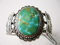 Photo of a large broken Turquoise cabochon in a silver bracelet.