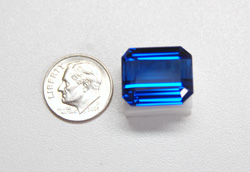 The finished Tanzanite sitting next to a dime.
