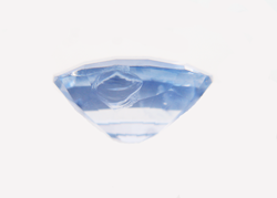 Photo of a light blue Sapphire with a chip in the side of the pavilion.