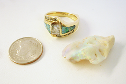The ring and a piece of Opal rough material next to a quarter.