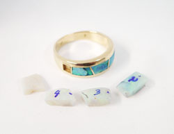 The photo shows pieces of rough Opal material which are sitting next to the ring, ready to be inlaid.