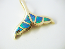 A pendant in the shape of a whale tail with one of the Opal inlays broken.
