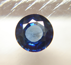 Photo of a round blue Sapphire which is windowed.