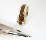 A 14 karat white gold wedding band inlaid 360 degrees around with petrified dinosaur bone.