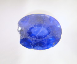 An oval blue Sapphire which is badly chipped and scratched on top.