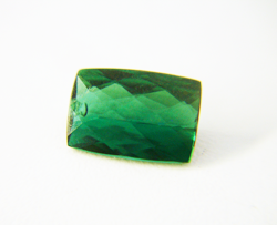 Shows a green Tourmaline cushion cut with a chip in the crown.